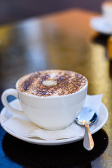 A cup of cappuccino coffee on a table, close up. 