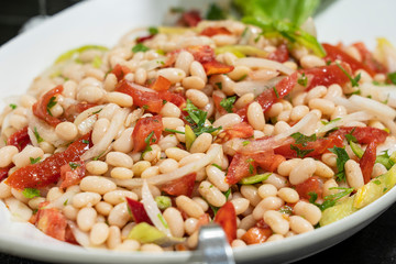 Boiled beans with tomatoes, greens, onions and peppers, closeup. Food concept
