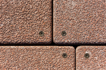lose up of large red stone and concrete pavers with brass screws at each corner