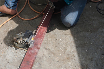 The welder with black cloth glove is welding the hinge steel with orange and black line on floor. It made a little splinter fire.