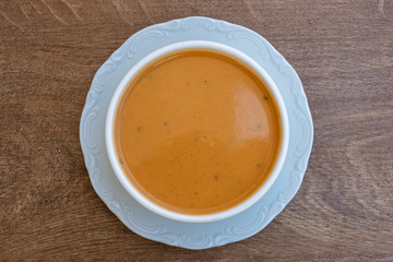 Vegetable cream soup with tomato, potato, squash in a white bowl, closeup