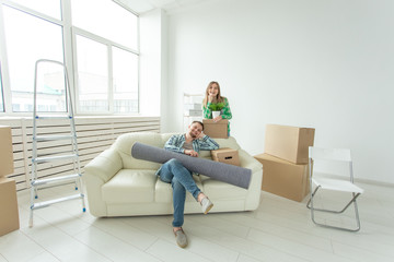 Satisfied cheerful young couple strong man and pretty woman holding their things in their hands sitting in the living room of a new apartment. Housewarming concept.