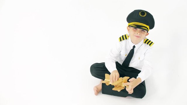 Boy wearing pilot's uniform plays with generic wooden toy plane