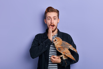 ginger guy being surprised with unusual present which has been given him by his friends. close up photo. isolated blue background, studio shot