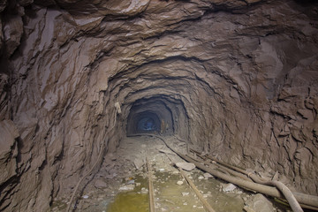 Gold ore mine shaft tunnel underground with rails