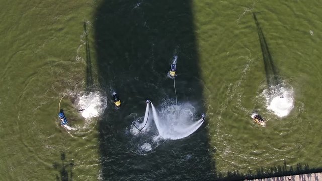 people perform complex tricks on flyboards.