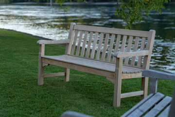 Two wooden benches in foreground on the river bank at sunset in autumn.