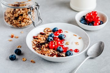 Healthy breakfast bowl with granola, blueberries, red currants and yogurt.