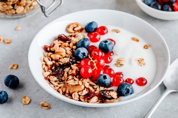 Healthy breakfast bowl with granola, blueberries, red currants and yogurt.