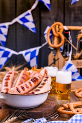 Fresh craft beer. German sausages on the grill. Traditional German sausages and pastry brezel for a beer festival. Wood background and decor.