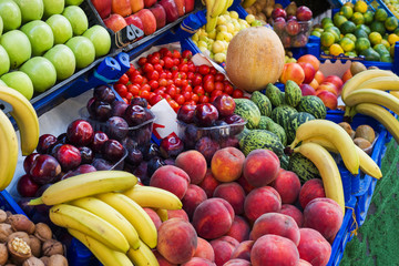 Fruits and vegetables on the counter of the street market. Bananas peaches nuts watermelon melon tomato apples plums.