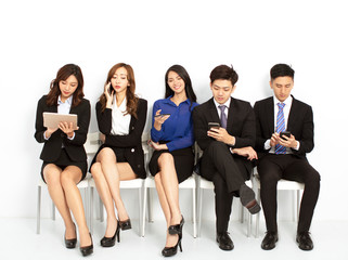  business people sitting on the chairs and using the smart phone