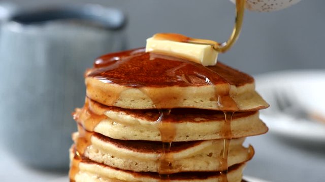Pancakes with butter and maple syrup. Pouring syrup on stack of fluffy buttermilk pancakes, american style breakfast