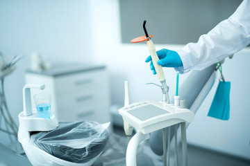 Fototapeta na wymiar Dentist in sterile gloves holding special dental equipment