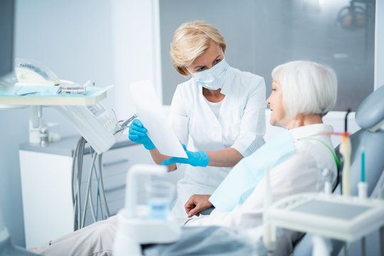 Female dentist talking with adult woman in clinic