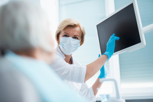 Dentist pointing a finger at the monitor screen