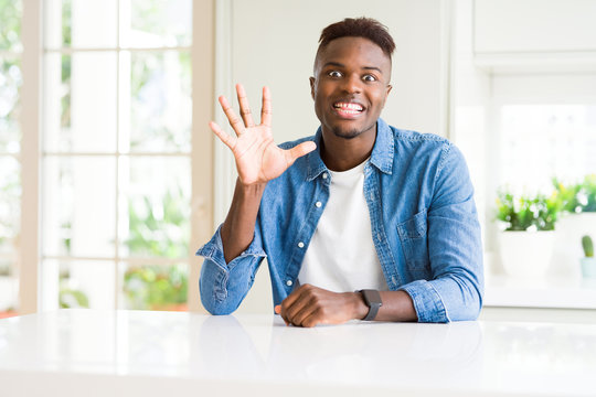 Handsome african american man at home showing and pointing up with fingers number five while smiling confident and happy.