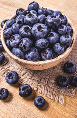 Raw fresh huckleberry in a bowl. Wooden background.