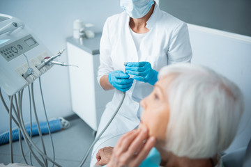 Stomatologist in sterile gloves is checking woman teeth