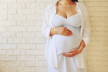 Cropped shot of young beautiful woman on third trimester of pregnancy. Close up of pregnant female...
