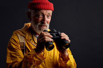 old hiker with tourist equipment looking at the camera, close up photo. isolated black background, studio shot