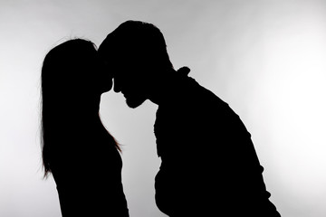 one caucasian couple man and woman kissing in studio silhouette isolated on white background.
