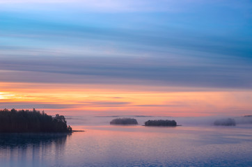 Long Exposure of Sunset at the Paijanne lake. Beautiful scape with sunrise sky, pine forest and water. Lake Paijanne, Finland.