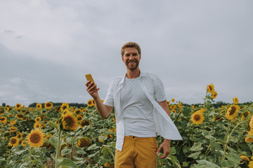 Happy young guy having rest in sunflower field
