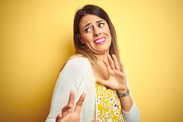Young beautiful woman wearing jacket standing over yellow isolated background disgusted expression,...