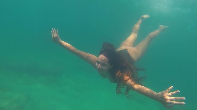 Beautiful woman swimming underwater in a tropical sea or river. Under water shot with action camera. Concept about wanderlust travels.
