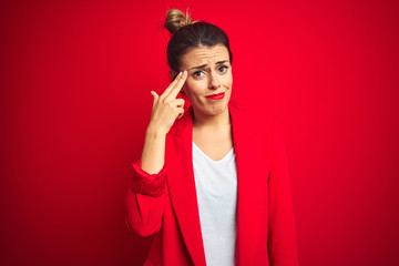 Young beautiful business woman standing over red isolated background Shooting and killing oneself pointing hand and fingers to head like gun, suicide gesture.