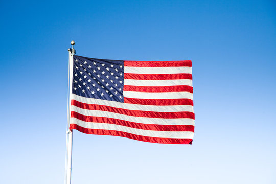 USA flag waving in the wind against blue sky on a sunny day