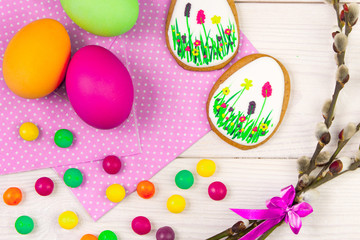 Easter background with Easter eggs and a willow twig. Easter gingerbread, eggs and willow twig on white wooden background. Easter Trend colors