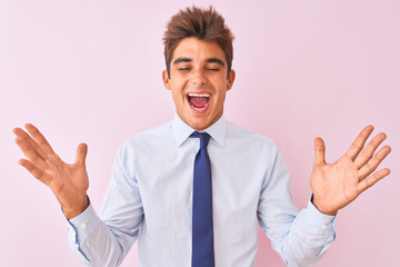 Young handsome businessman wearing shirt and tie standing over isolated pink background celebrating crazy and amazed for success with arms raised and open eyes screaming excited. Winner concept