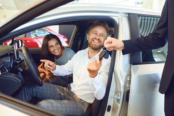 A happy couple bought a new car at a car showroom.