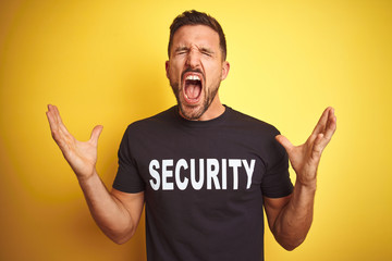Young safeguard man wearing security uniform over yellow isolated background celebrating mad and...