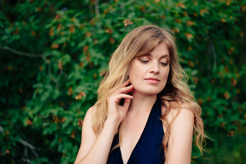 beautiful girl in a black dress outdoors in a park on a background of greenery