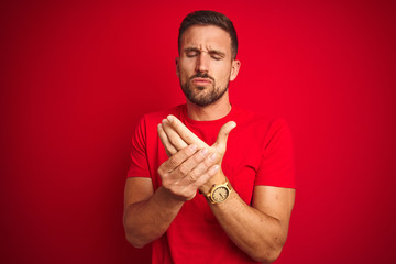 Young handsome man wearing casual t-shirt over red isolated background Suffering pain on hands and...