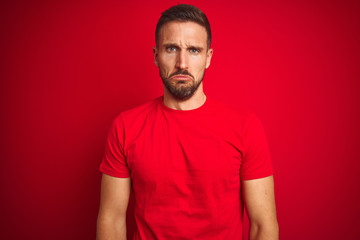 Young handsome man wearing casual t-shirt over red isolated background depressed and worry for distress, crying angry and afraid. Sad expression.