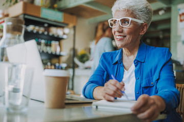 Positive lady making notes in cafe stock photo