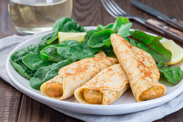 Savory crepe with shrimps and creamy dill sauce served with green leaves salad and lemon,  horizontal