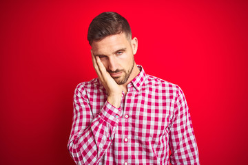 Obraz premium Young handsome man over red isolated background thinking looking tired and bored with depression problems with crossed arms.