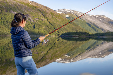 Woman fishing on Fishing rod spinning in Norway.