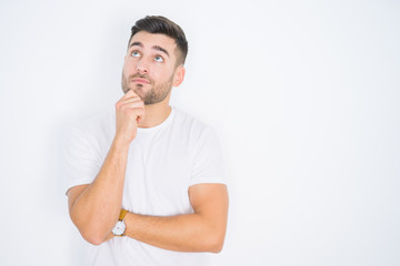 Fototapeta na wymiar Young handsome man wearing casual white t-shirt over white isolated background with hand on chin thinking about question, pensive expression. Smiling with thoughtful face. Doubt concept.