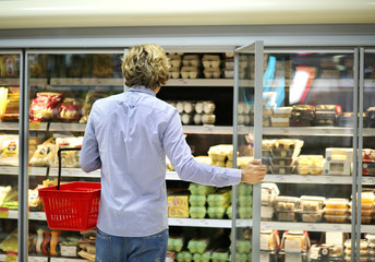 Man choosing frozen food from a supermarket freezer