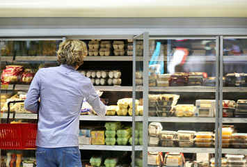 Man choosing frozen food from a supermarket freezer