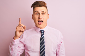 Young handsome businessman wearing shirt and tie standing over isolated pink background pointing finger up with successful idea. Exited and happy. Number one.