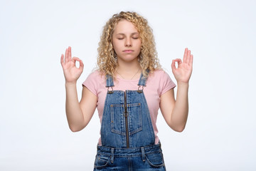 Portrait of a casual pretty woman meditating on white background. Studio shot