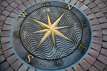 Fragment decorative compass points with compass rose directions, on the ground.