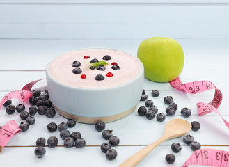 Naklejka na ściany i meble Yogurt with fresh of berries in blow ,green apple and measuring on wooden background,die lifestyle concept